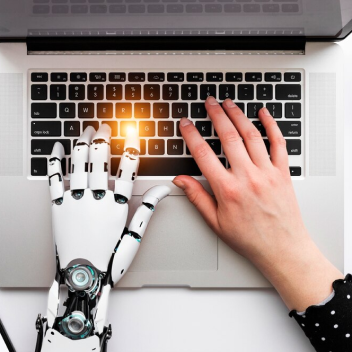 Mão de uma pessoa e um robô interagindo em um notebook